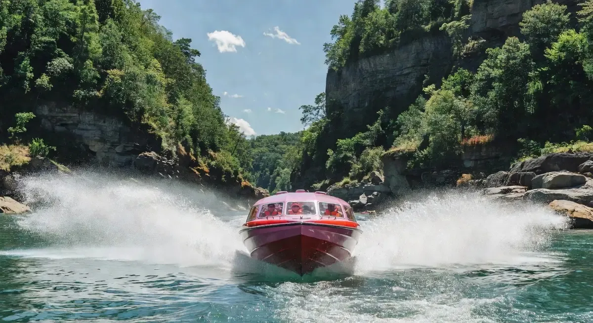 Pink Freedom Jet domed boat racing through the Niagara Gorge on a Niagara Falls jet boat tour — turquoise river and forested gorge walls