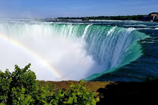 Tourists in blue ponchos on the Maid of the Mist boat ride at the base of Horseshoe Falls on a Niagara Falls American side tour